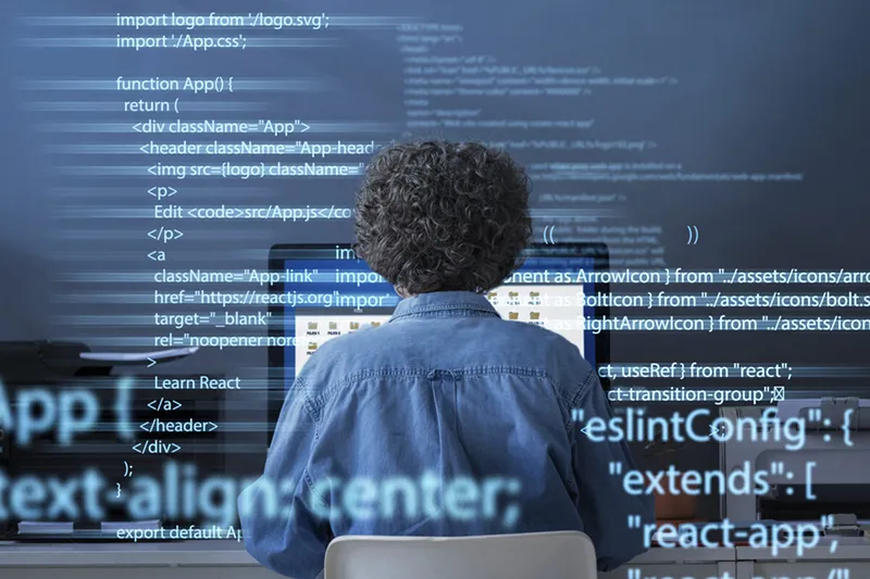 A Java Script Developer from Latin America sitting at a computer desk in a blue shirt.