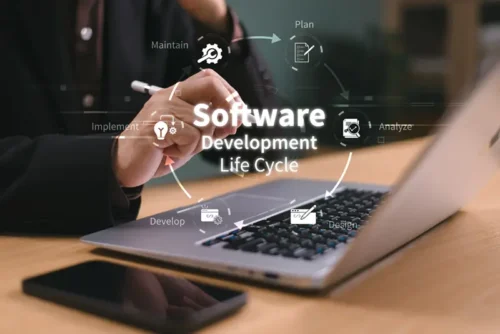 A tech worker at a laptop computer with a graphic image of the circular Software Development Life Cycle symbol overlaid in the forefront.