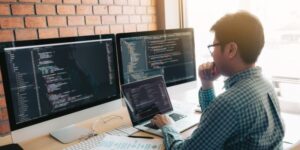 A web developer sitting at multiple computer screens