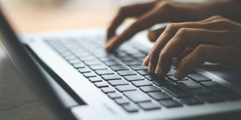 Hands typing on a laptop representing nearshore BPO solutions.