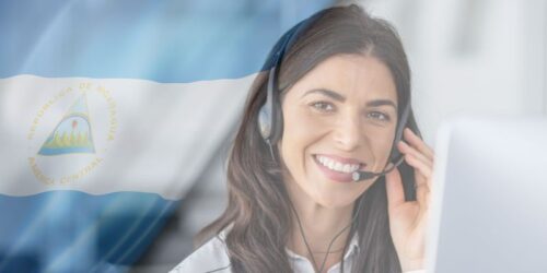 alt= A woman wearing a headset smiles, embodying the spirit of BPO nearshoring, set against a blurred Nicaraguan flag background.