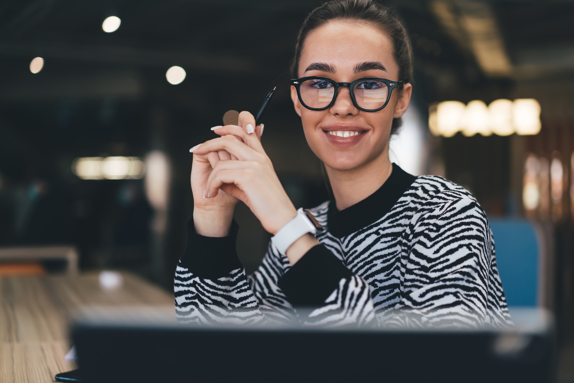 Cheerful young woman with laptop in office