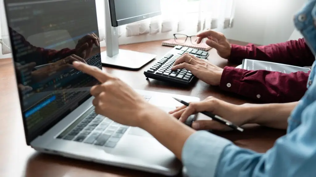 The hands and keyboards of a fullstack dev team in Argentina are shown finding solutions to coding.