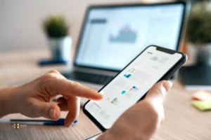 A nearshore mobile app develop looks at a phone while working on computer